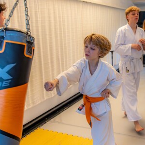 little child boy in a white karate kimono training. Full length portrait