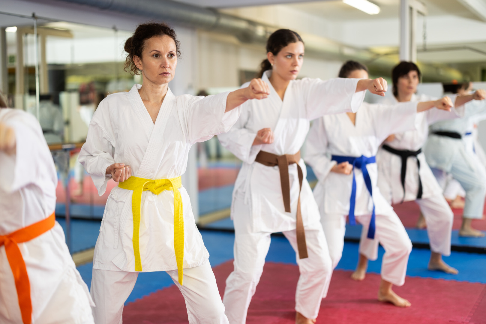 Group of women in kimonos train karate techniques in studio